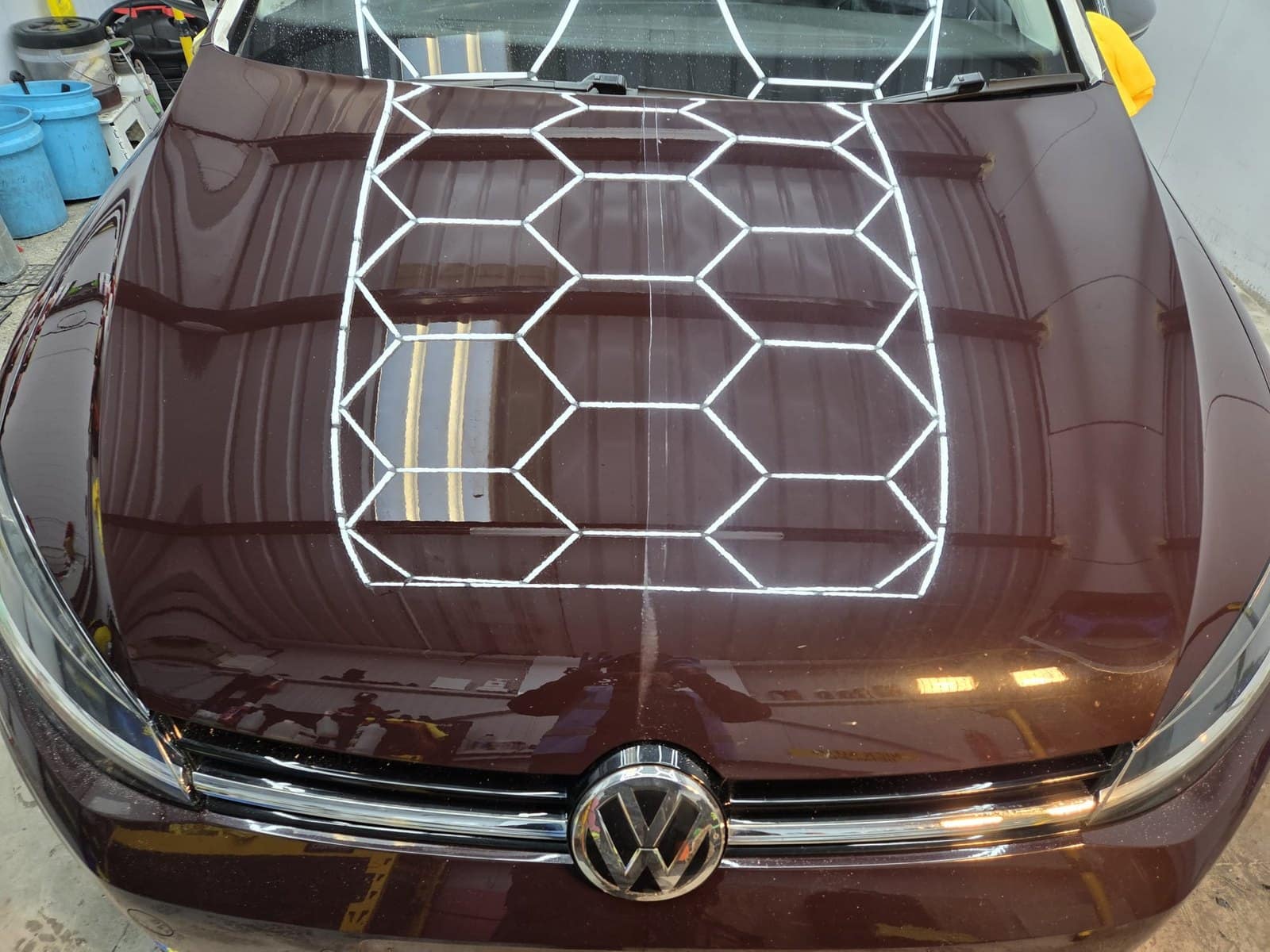 A maroon Volkswagen Golf bonnet with a deep gloss under the studio's hexagon lights