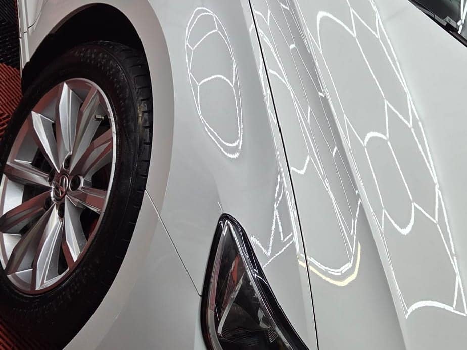 A white saloon's front wing under the studio lights in Connah's Quay