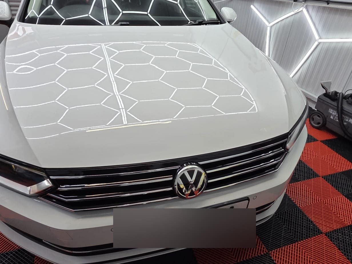A white Volkswagen Passat bonnet with the studio's hexagon lights reflected in it