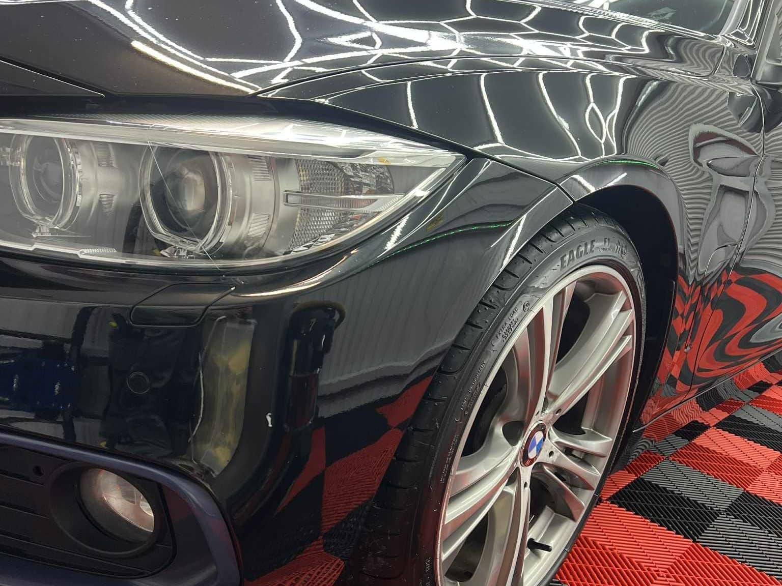 Deep gloss on a black BMW's front wing under the studio lights