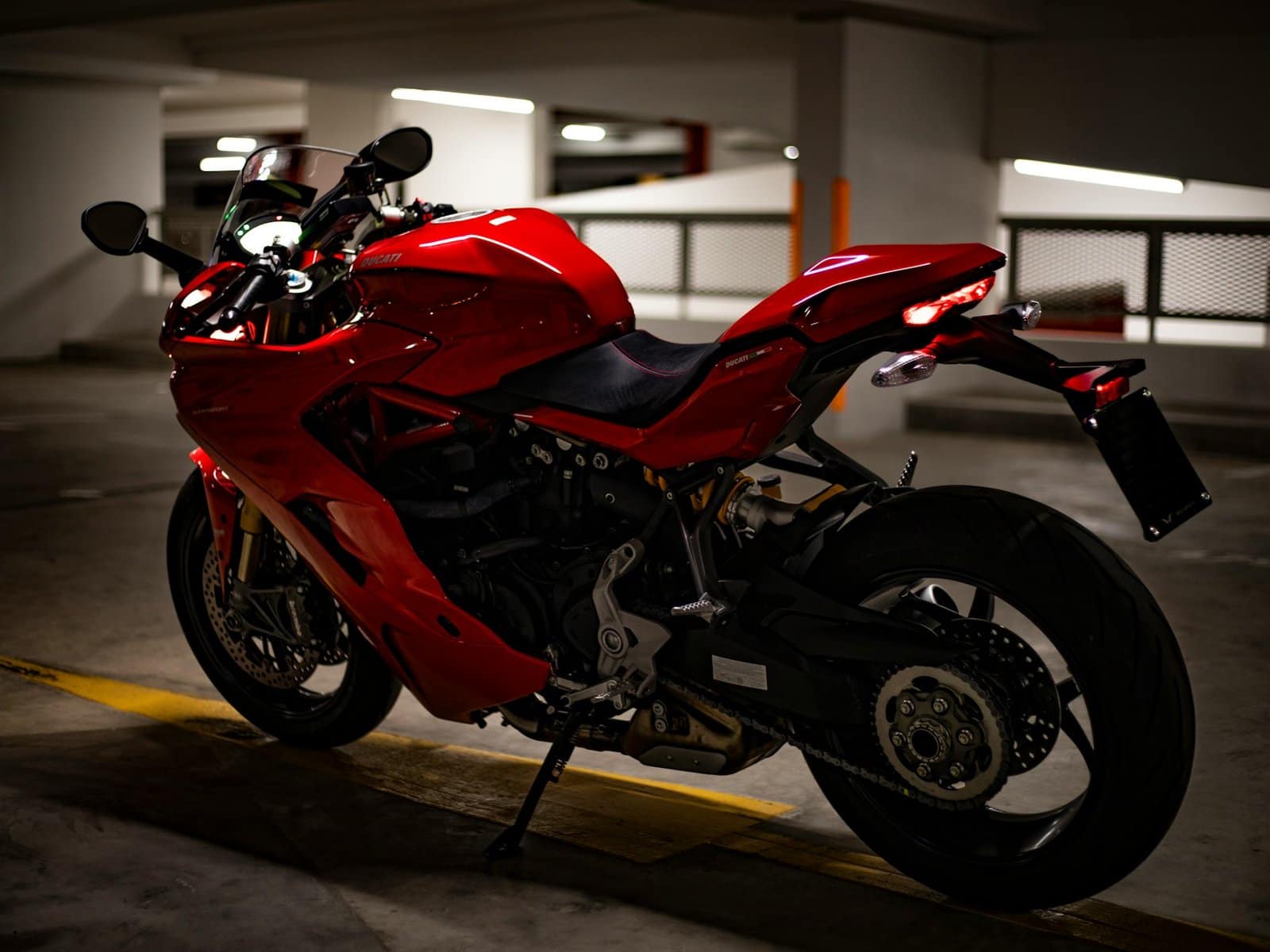 A red Ducati sports bike with glossy paint, parked in a car park