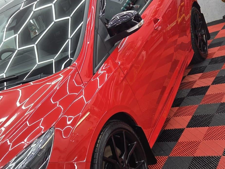 A red Ford Focus RS with paint protection film fitted, the studio lights reflected across the bonnet and door