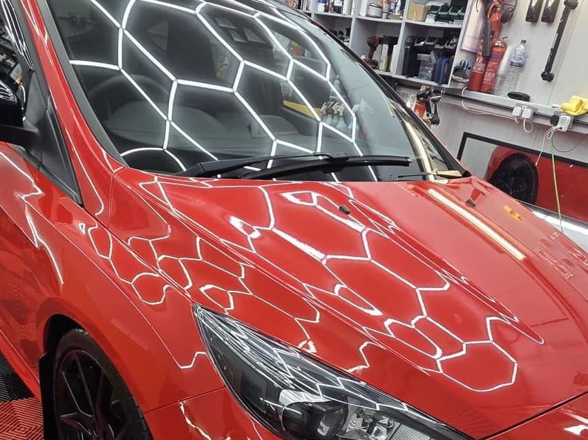 A red Ford Focus RS with paint protection film, under the studio lights